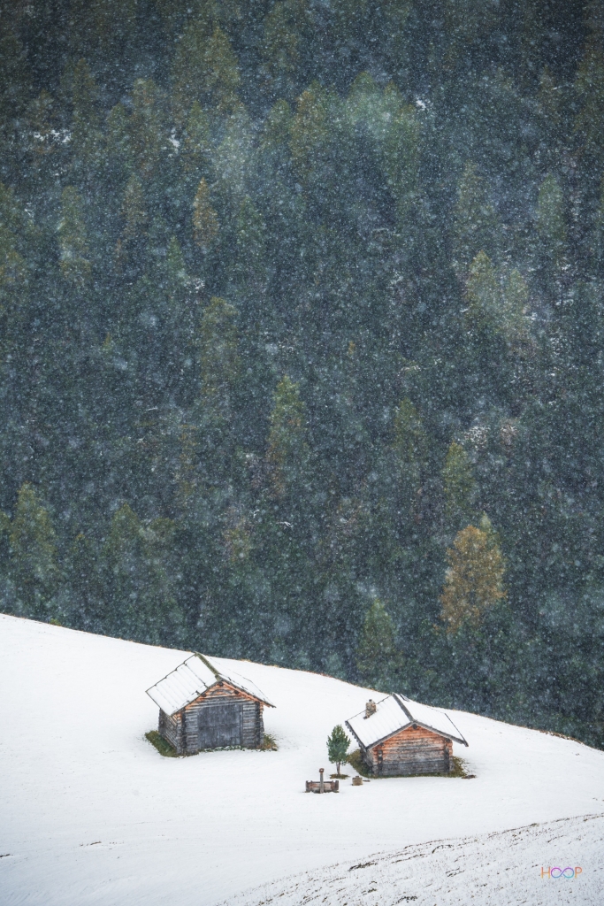 Two mountain huts covered in snow.